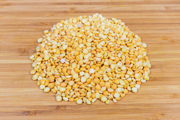 Pile of yellow split peas on a wooden surface