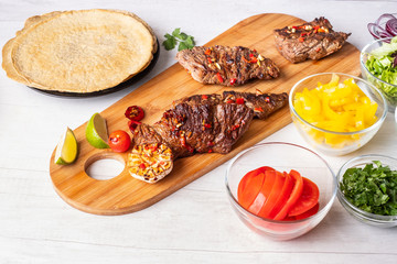 Street food - Mexican tacos with meat in sauce and vegetables salsa with ingredient cooking on white background.