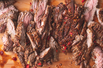 Slices of grilled beef meat on wooden desk background. Top flat lay view.