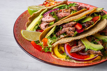 Tacos with grilled meat, avocado, fresh salsa sauce and limes over rustic background. Healthy low carb and low fat lunch or food for company. Dieting and weight loss concept