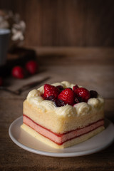 strawberry layer cake topping strawberry putting on the white plate on the wood table background.