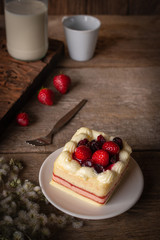 strawberry layer cake topping strawberry putting on the white plate on the wood table background.