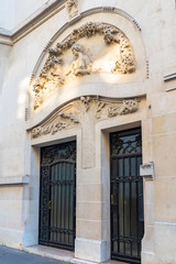 Fototapeta na wymiar Paris, beautiful door rue Alfred Dehodencq, Art nouveau style, with sculptured stone on the girder