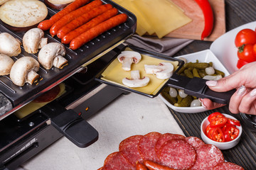 young woman is preparing a traditional Swiss cheese raclette