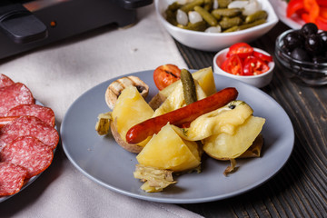 young woman is preparing a traditional Swiss cheese raclette