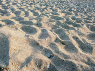 Background of beach sand with small pebbles. Indentations on the sand (craters).