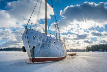 Old and broken abandoned ship on ice at sunny winter day in coastline Finland. - 263644829
