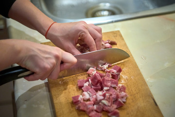 cutting meat on a kitchen board with a knife