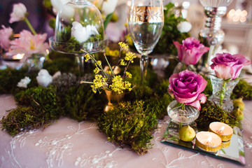 Rustic decoration (forest moss, flowers, candles, glasses and vases). Evening romantic atmosphere.