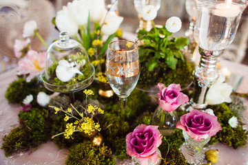 A gentle and romantic decoration from the moss and fresh flowers of the evening table in a beautiful light restaurant