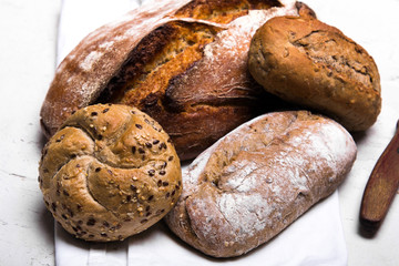 Tasty dark bread and buns  on white background, copy space. Bakery products, wholemeal bread and brown whole wheat buns