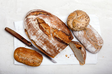 Tasty dark bread and buns  on white background, copy space. Bakery products, wholemeal bread and brown whole wheat buns