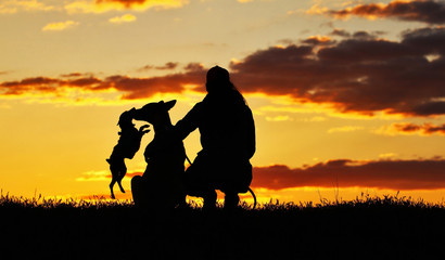Silhouettes girl and two dogs at sunset, a breed of Belgian Shepherd dog Malinois and a miniature pinscher dog, an incredibly beautiful sunset, best friends together