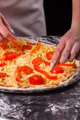 young woman in a gray aprong prepares a vegetarian pizza