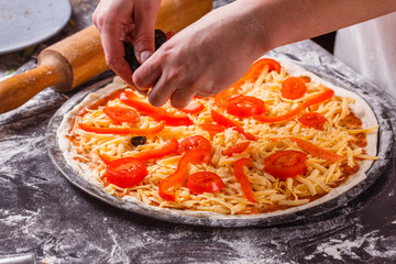 young woman in a gray aprong prepares a vegetarian pizza