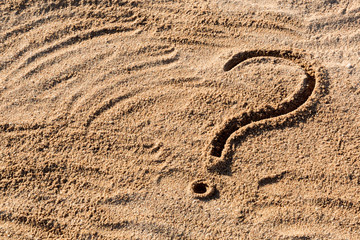 Fototapeta na wymiar question marks written on beach sand close up, with copy space