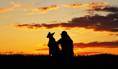 Fototapeta na wymiar Silhouettes of girl and dog at sunset, breed Belgian shepherd Malinois, incredibly beautiful sunset, best friends together