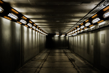 empty spooky dim concrete underground walkway tunnel passage with led lamps