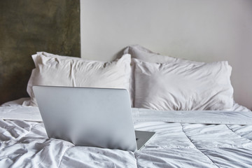 Fototapeta na wymiar Laptop on white bed work at home concept
