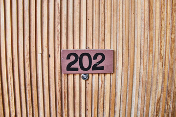 Sign on the wooden door. Room number in the hotel.