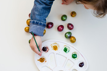the child paint easter eggs by brush and paints