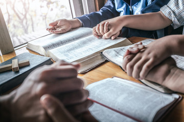 Christian group praying together around table at home, prayer meeting concept.