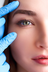 Upper eyelid reduction, double eye lid removal plastic surgery concept. Beautician doctor hands in...