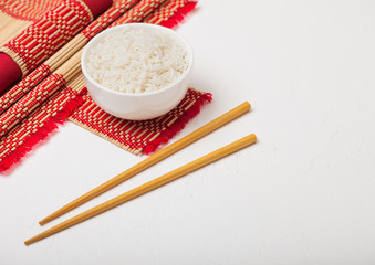 White bowl with boiled organic basmati jasmine rice with wooden chopsticks and sweet soy sauce on...