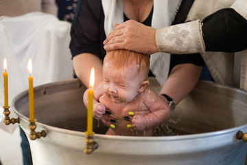 Newborn baby baptism in Holy water. baby holding mother's hands. Infant bathe in water. Baptism in...