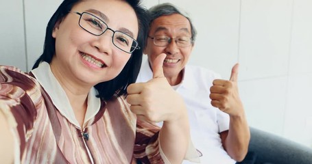 Senior Asian people recording a Selfie video, They make a hand symbol as love sign, thumps up, and good bye, concept for happy retire. - Powered by Adobe