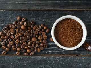 Freshly ground coffee in a mug and coffee beans on a wooden table