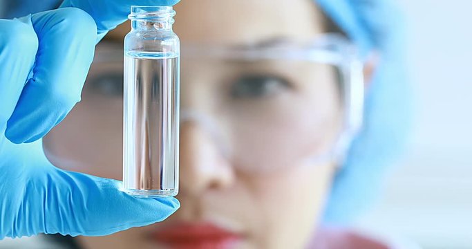 Asian female scientist moving sample tube for her experiment in laboratory room.