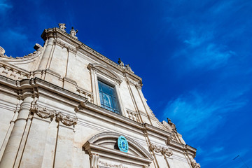 Fototapeta na wymiar Beautiful facade of building in Puglia. Mediterranean architecture of Southern Italy. Scenery summer blue-sky day with expressive clouds. Day street alleyway view, European travel photography