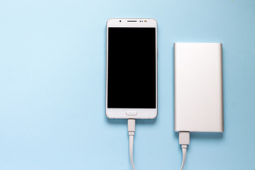 Smartphone and power bank on a blue background. Top view of the place for the text. Flat lay