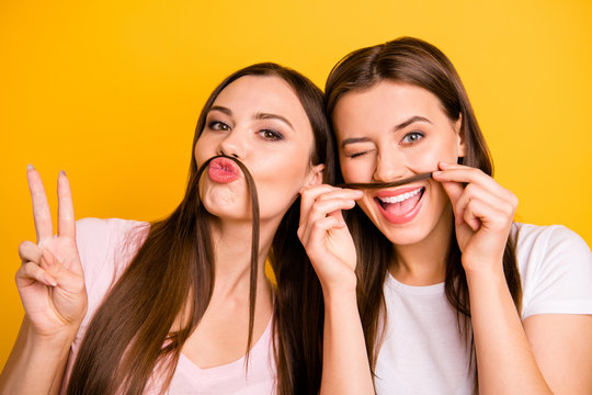 Close up photo two people beautiful she her ladies models send air kisses playing make fake moustache crazy winking eye show v-sign wear white pink casual t-shirts isolated yellow background - Powered by Adobe
