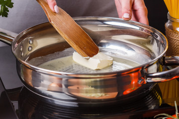 young woman in a gray apron puts butter in a frying pan