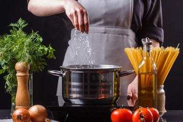young woman in a gray apron preparing pasta
