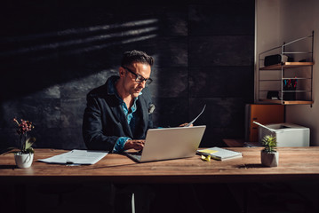 Businessman sitting at his desk and using laptop in the office