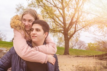 A young man piggybacks his young girlfriend