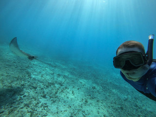 Freediver taking selfie with a stingray in a crystal water. Concept of travel and vocation