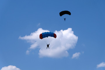 Two parachutists are in the sky.