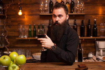 Young tattooed bartender with great beard tasting a glass of wine.