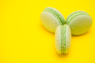 Sweet and delicious green macaroons over yellow background