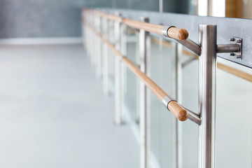 Ballet wooden barre by mirror in dance class room. Blurred background of ballet modern school.