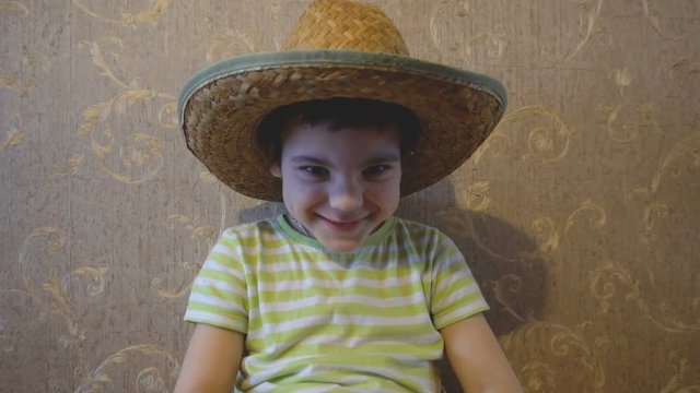 The boy in the straw hat. Changing the image. The grimace on her face. Bad character. Against the wall with Wallpaper. Rustic image. 4K video