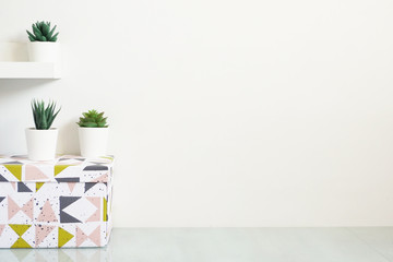 Wooden desk table top with tree pot on white wall, with copy space