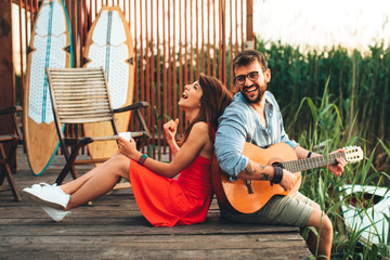 Man and woman singing and playing guitar by the river