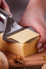 young woman slicing cheese in a gray apron