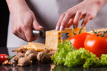 young woman slicing cheese in a gray apron
