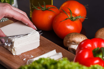 young woman slicing cheese in a gray apron
